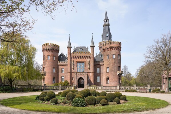 A castle with multiple towers, a central entrance, and a well-maintained garden.