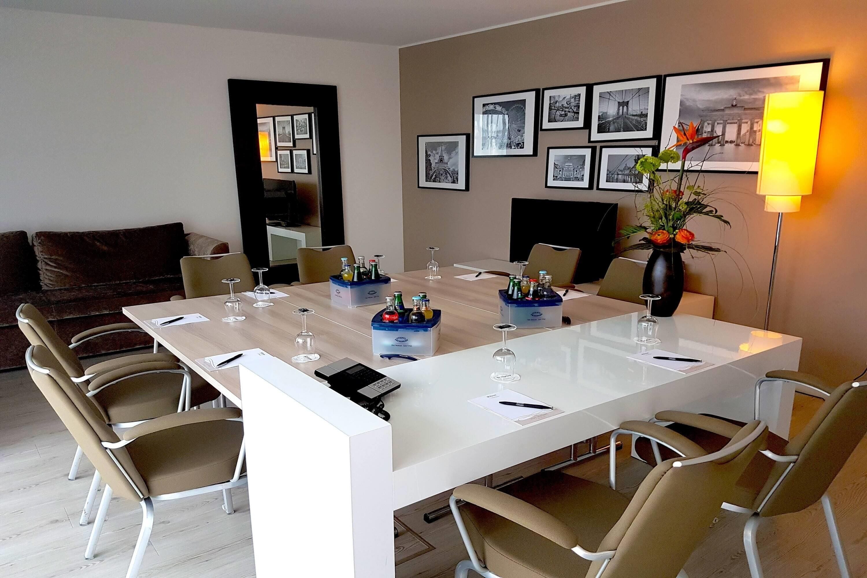 Een moderne eetruimte met een witte tafel, meerdere stoelen en een vaas met bloemen.
