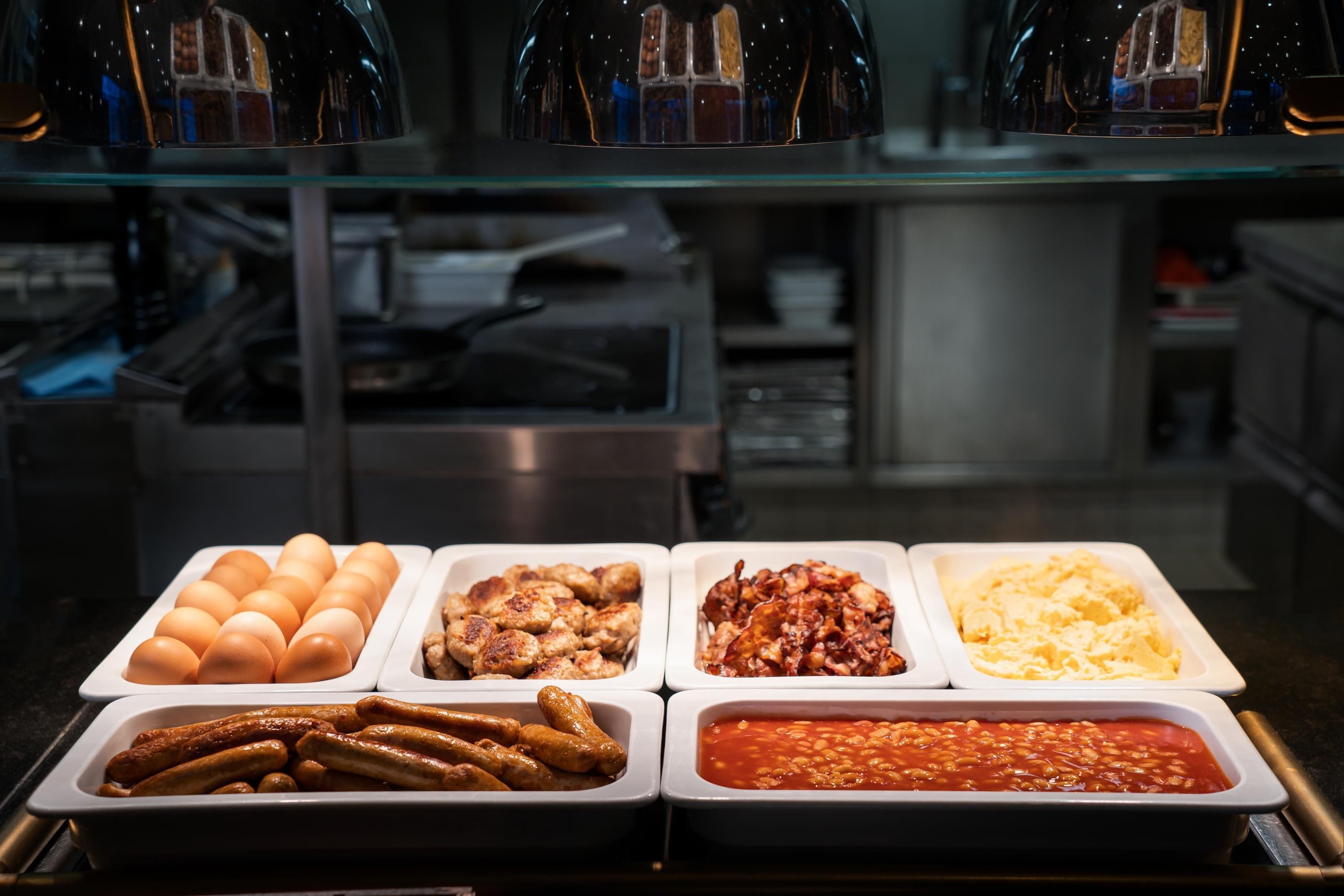 A buffet with various food options including eggs, sausages, and baked beans.