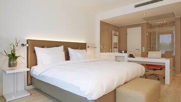 Una habitación de hotel moderna con una cama grande, mesitas de noche, un escritorio y una zona de ducha.