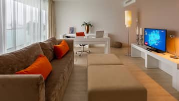 Una sala de estar moderna con sofá, reposapiés, mesa de centro y un televisor mostrando un mapa.
