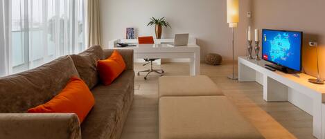 A modern living room with a sofa, ottoman, coffee table, and a TV displaying a map.