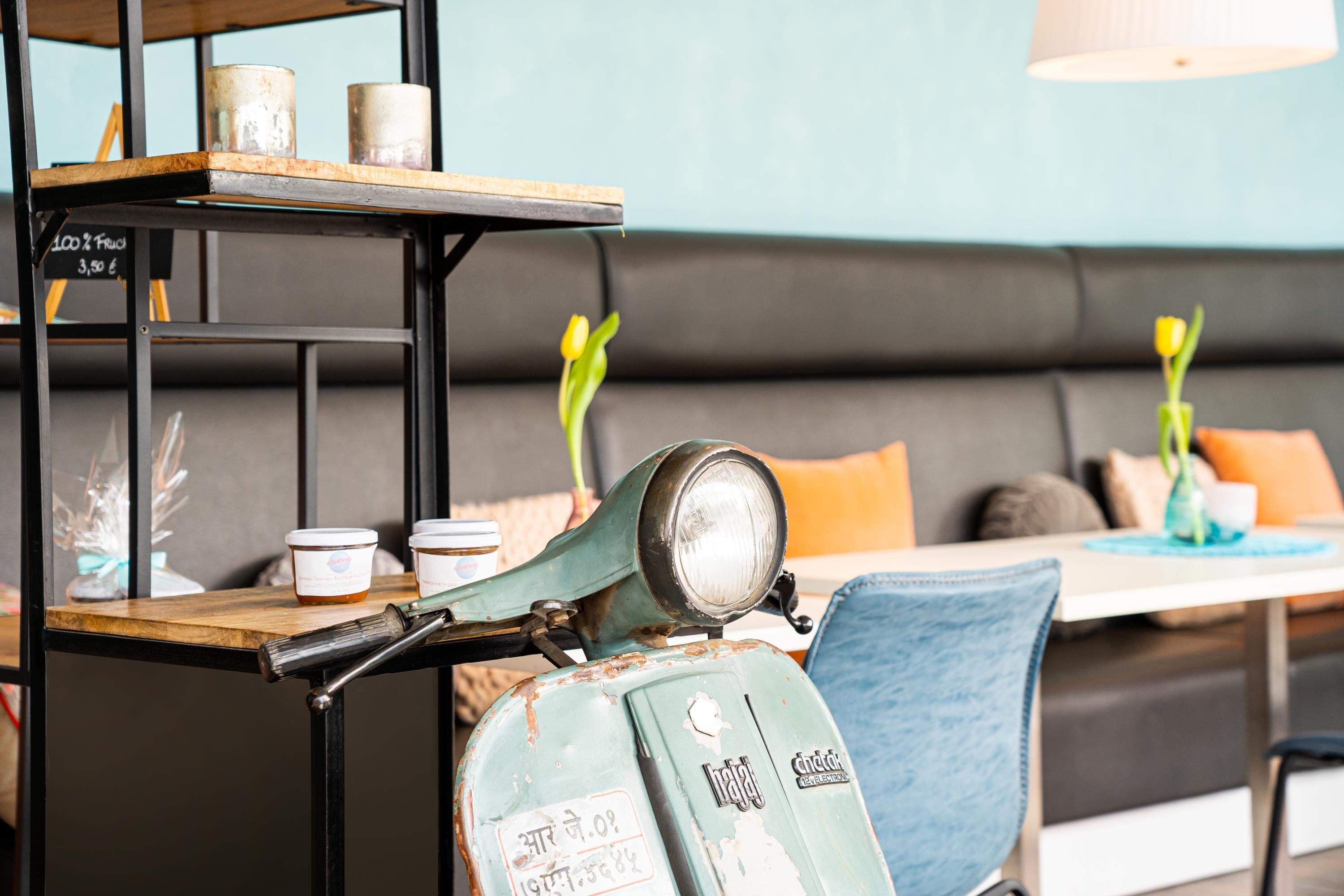 Un scooter vintage, doté d’un phare et d’une enseigne avec du texte, est posé sur une table en bois dans un café.