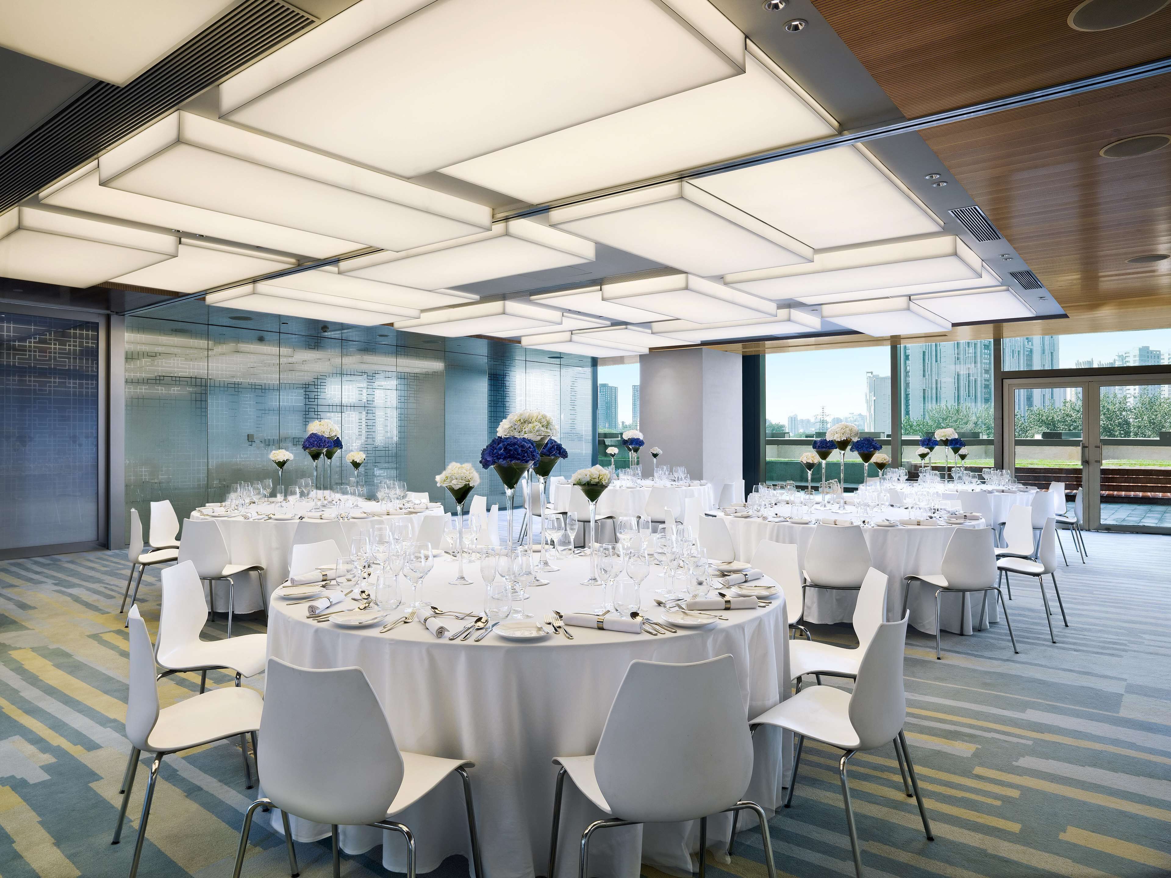 A conference room with multiple round tables, white chairs, and floral centerpieces.