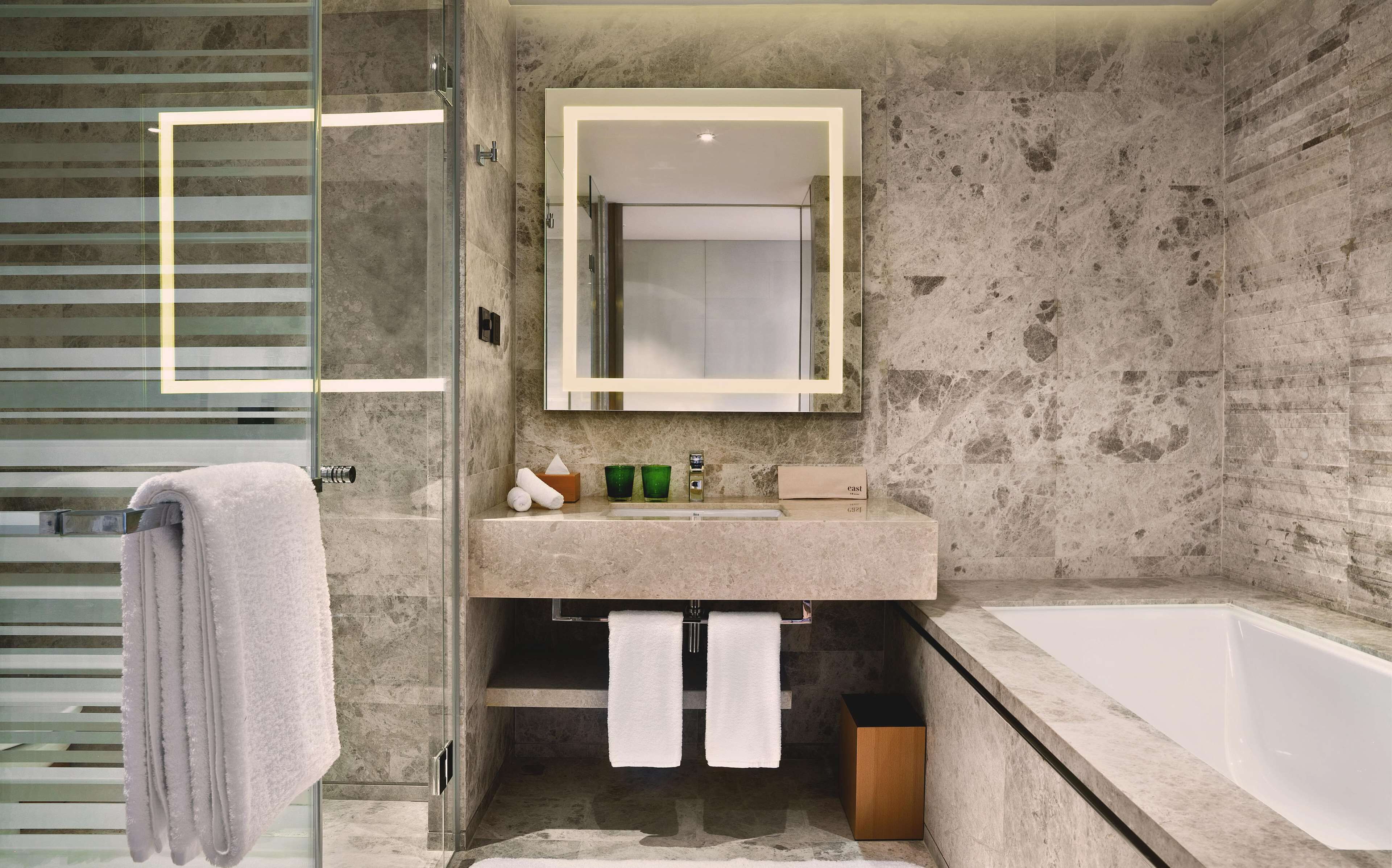 A bathroom with a glass shower enclosure, a marble sink, and a bathtub.