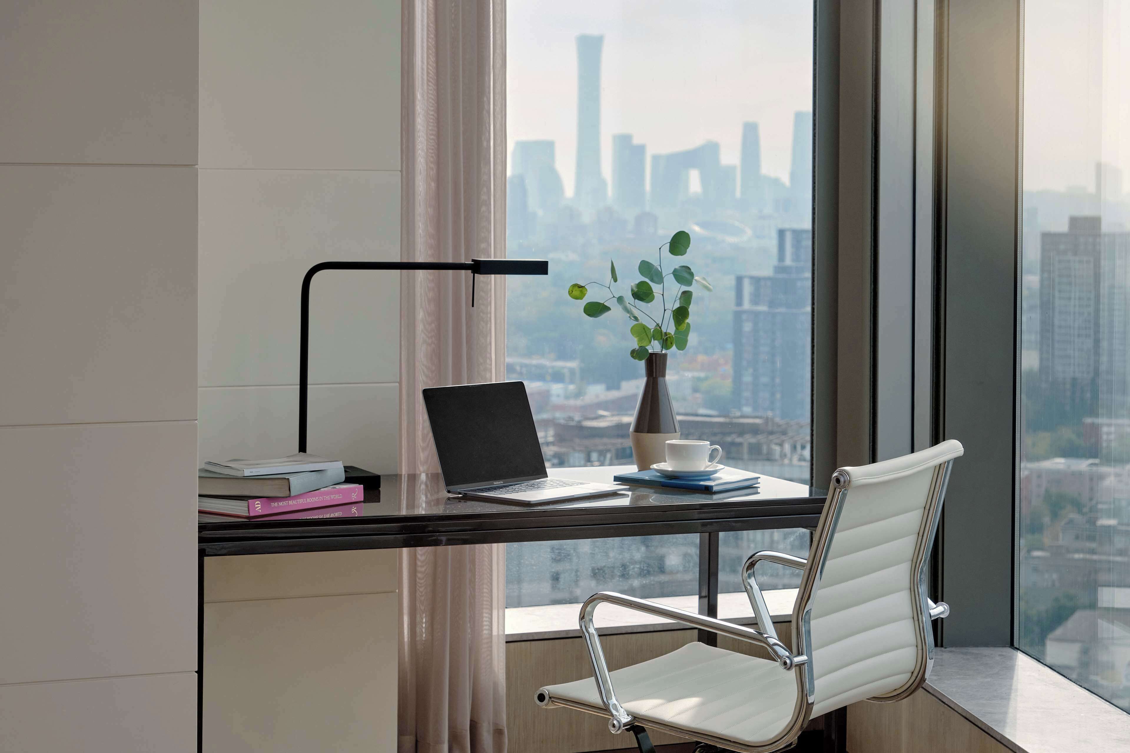 A modern office space with a desk, laptop, books, a plant, and a chair.