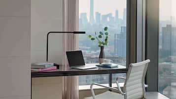 A modern office space with a desk, laptop, books, a plant, and a chair.