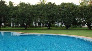 A swimming pool surrounded by lush greenery and a building in the background. - Baia Do Sol - Beach Boutique (Baga)