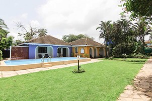 Un edificio de dos pisos con piscina, césped cuidado y un camino que lleva a la entrada.
