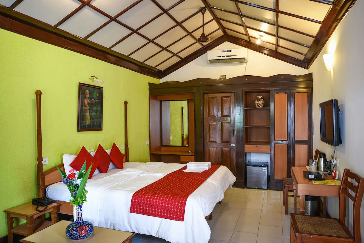 Una habitación de hotel con cama, escritorio, silla, televisor y baño.