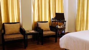 A hotel room with two wooden chairs, a small table, and a bed. - Villa Paradiso (Dharamshala)