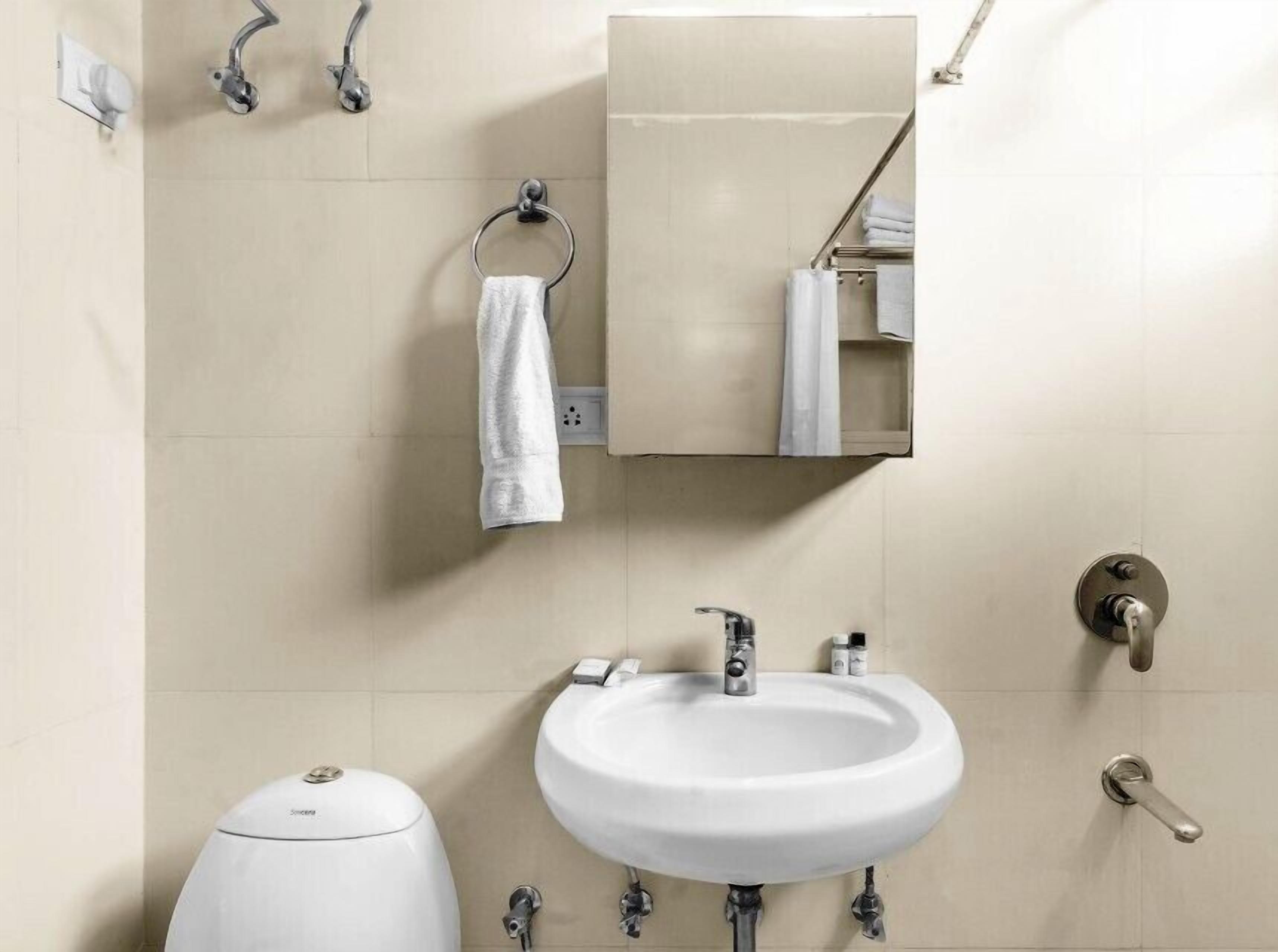 A bathroom with a white sink, a mirror, a towel ring, and a toilet.
