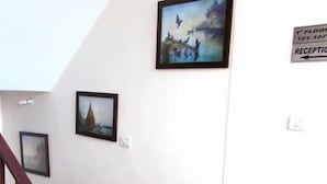 A staircase with a wooden handrail leading to a landing. There are three framed pictures on the wall above the staircase. - Villa Paradiso (Dharamshala)
