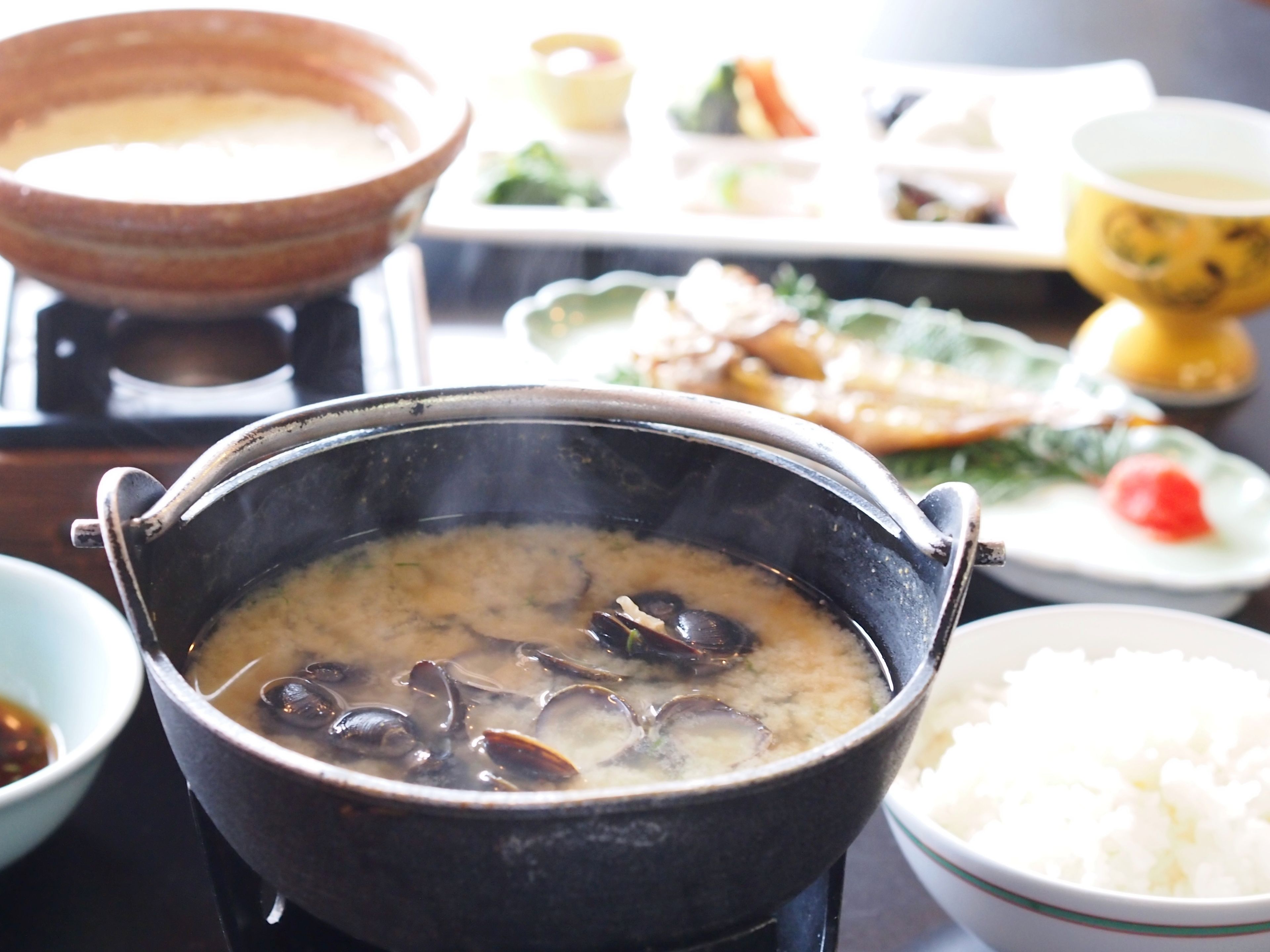 Un plat japonais traditionnel, préparé dans un récipient chauffé à table, contenant des fruits de mer, du riz et divers accompagnements.