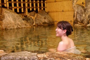 A person in a stone bath with bamboo walls and large rocks. - Hanaya Bekkan (Misasa)