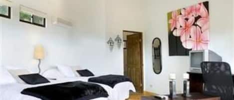 A hotel room with two beds, a desk, a chair, a TV, and a large floral painting on the wall.