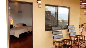 Um quarto com uma cama, duas cadeiras e uma janela com vista.