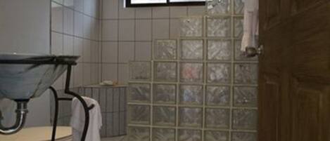 Un baño con cabina de ducha de vidrio, un lavabo con espejo y suelo de baldosas.