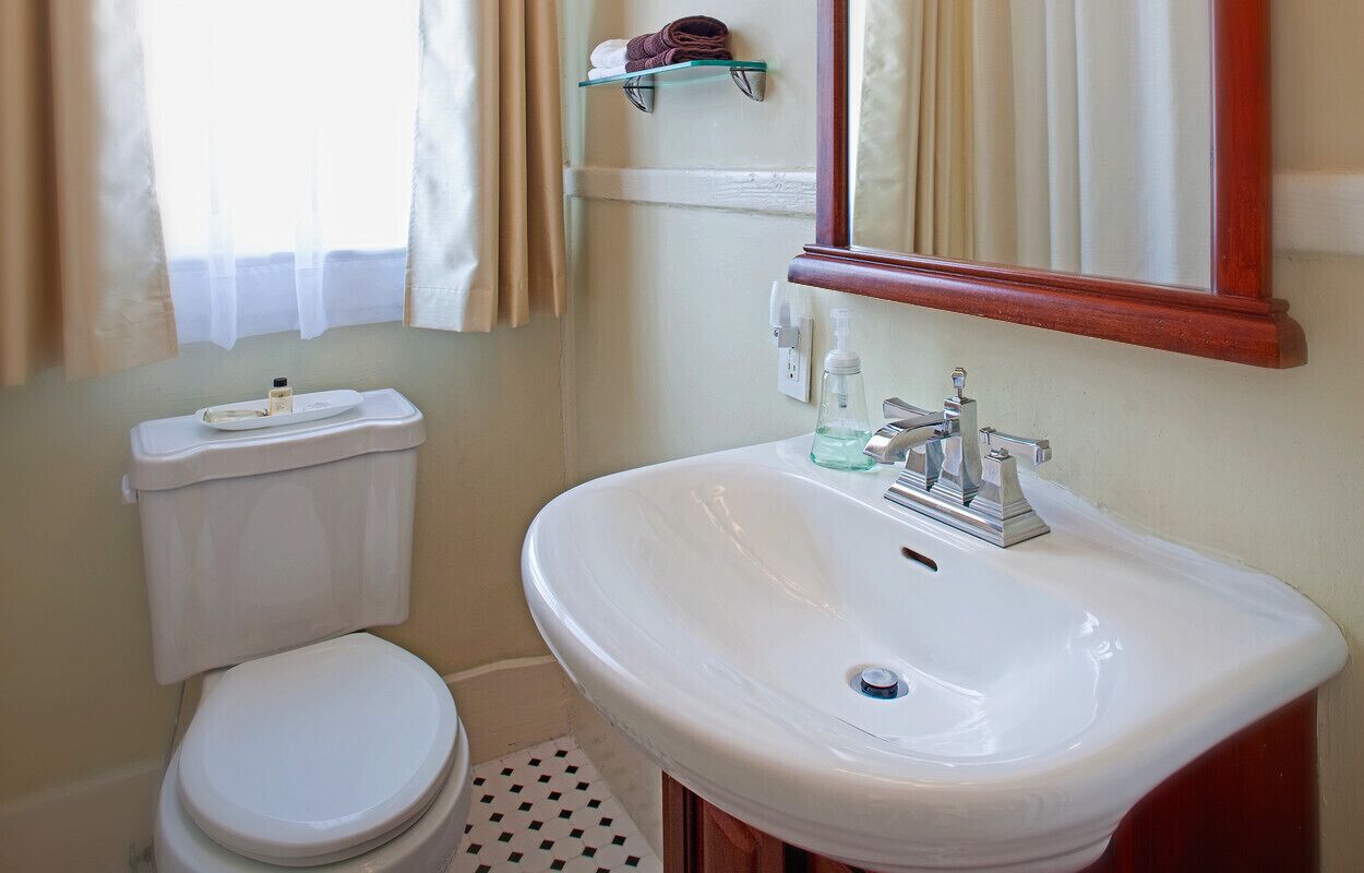 A bathroom with a toilet, a white sink, and a mirror.