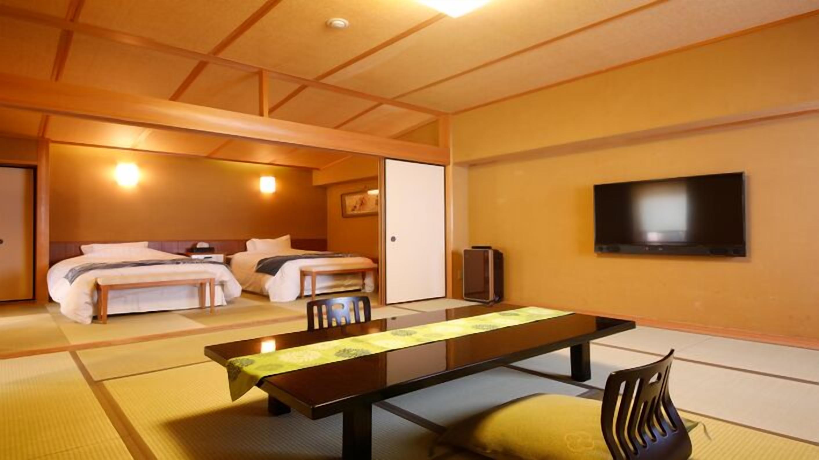 A hotel room with two beds, a flat-screen TV, a wooden table, and tatami mats.
