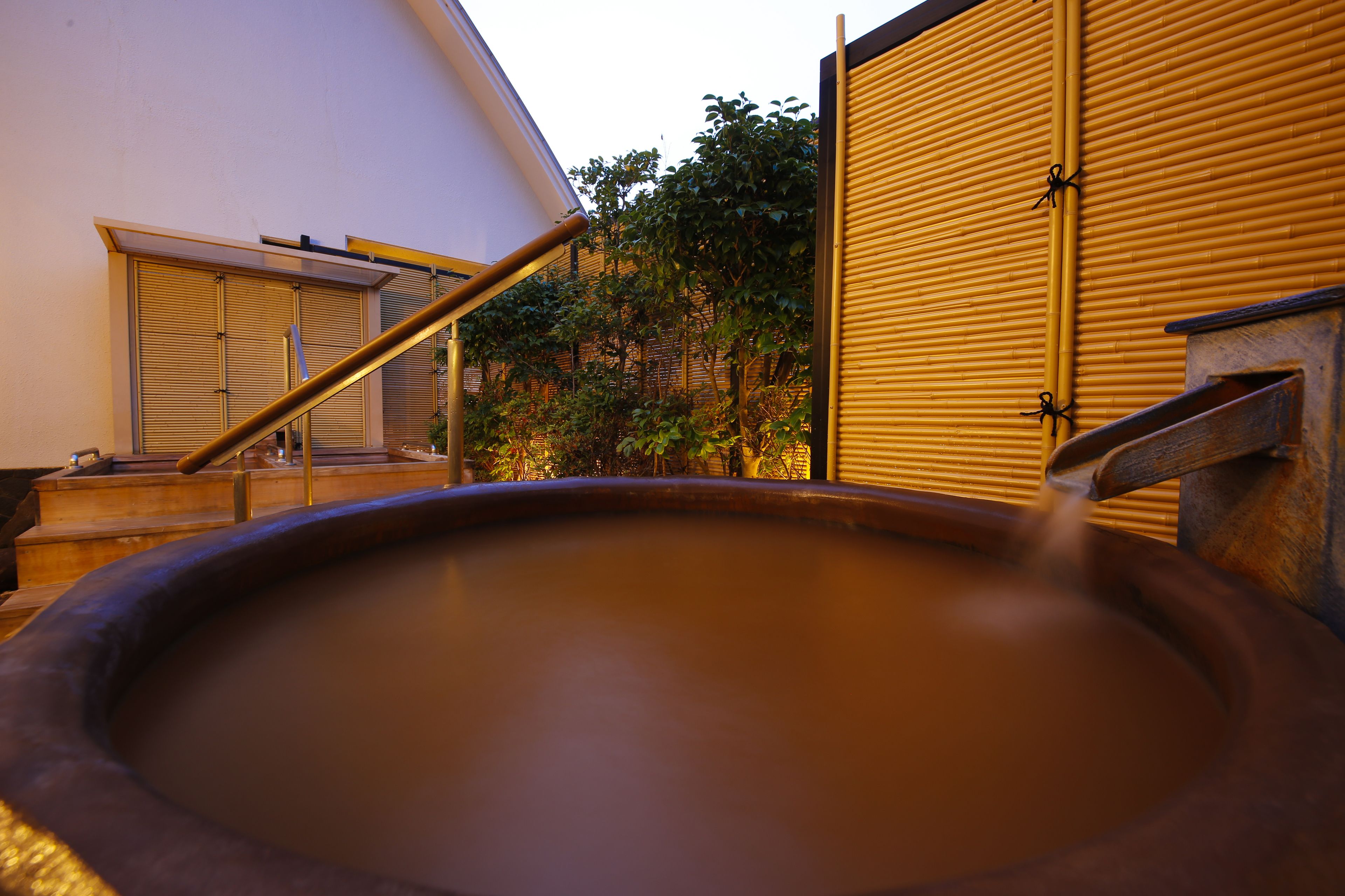 A hot spring with a wooden bench and a metal railing.