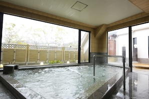 A hot tub area with a view of a bamboo fence and trees outside.