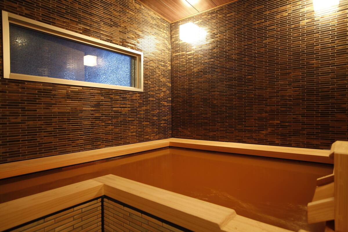 Un espacio de spa con un banco de madera, una ventana y una pared con azulejos.