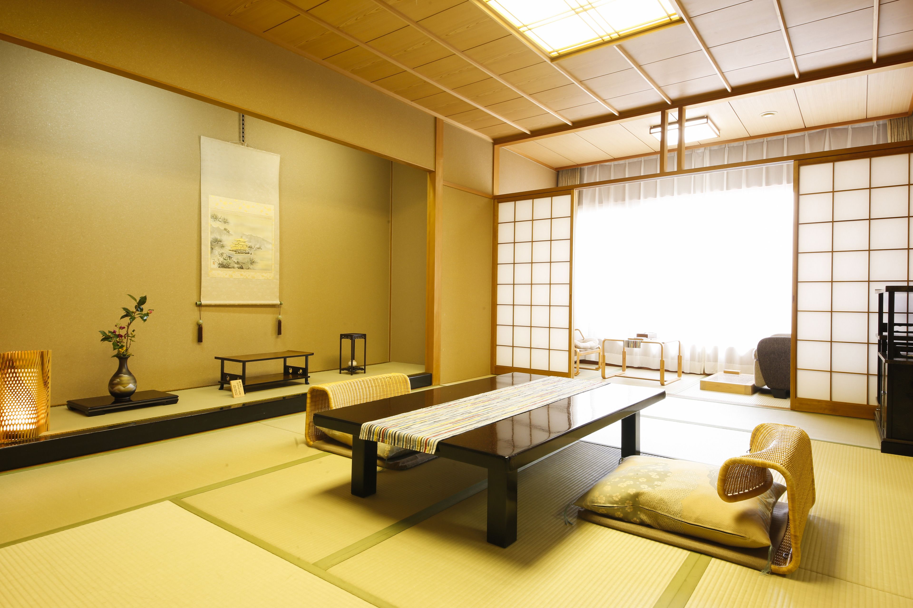 A traditional tatami mat room with a low table, cushions, and sliding doors.