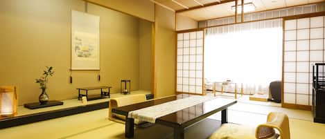 A traditional tatami mat room with a low table, cushions, and sliding doors.
