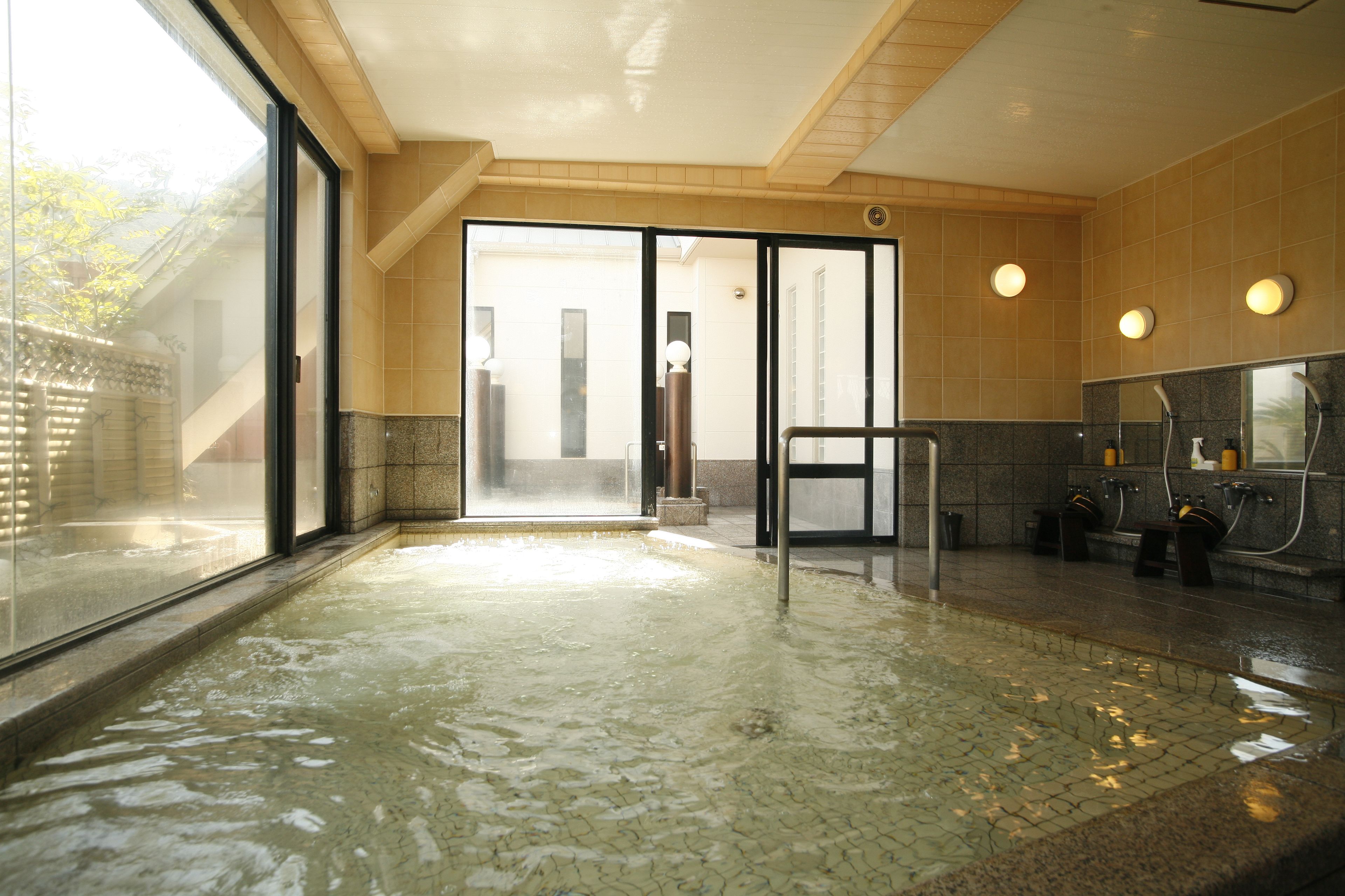 Área de spa com hidromassagem, piso revestido e porta de vidro que dá para o exterior.