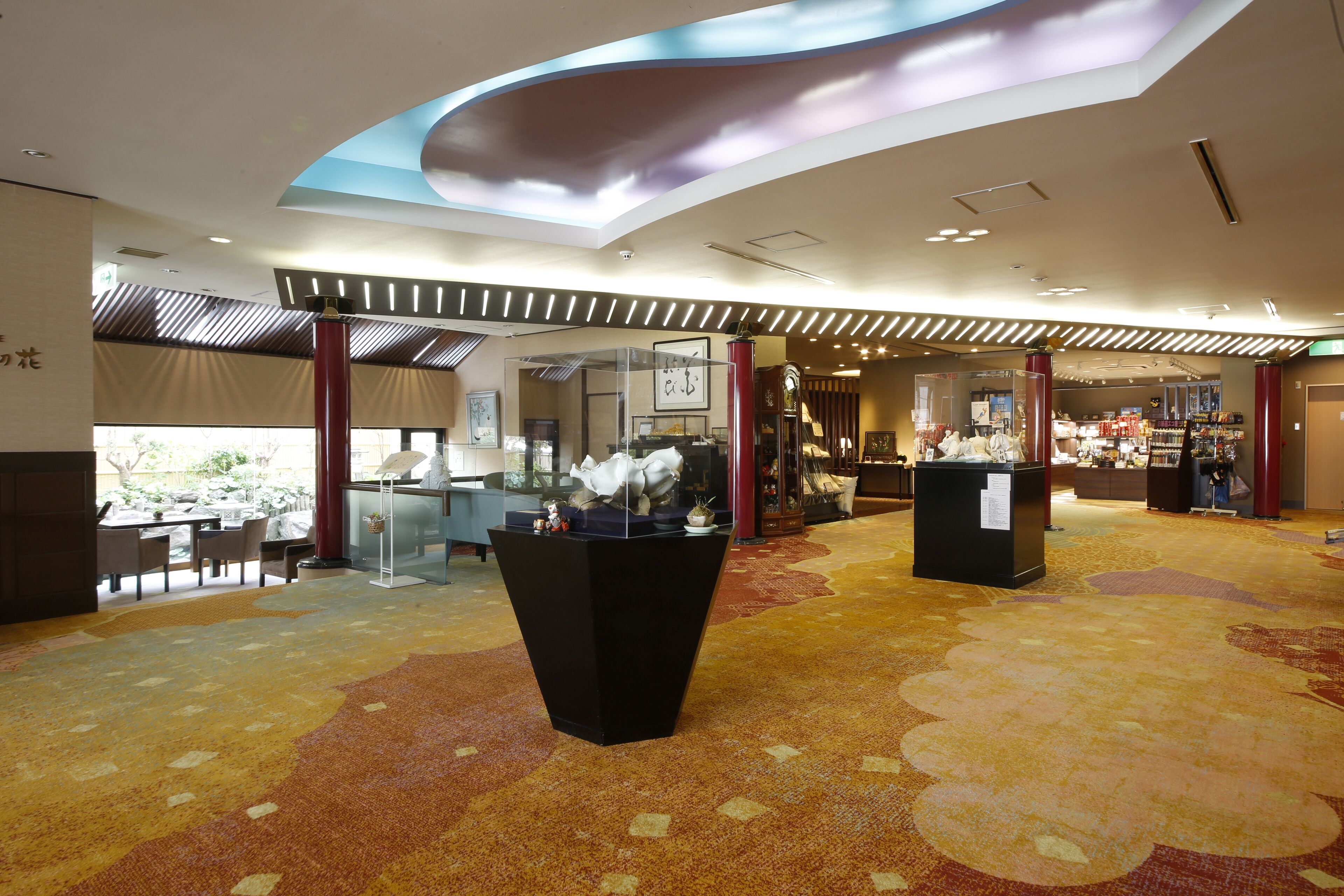 Een hotel lobby met een gebogen plafond, een receptiebalie, een zithoek en een display toonbank.