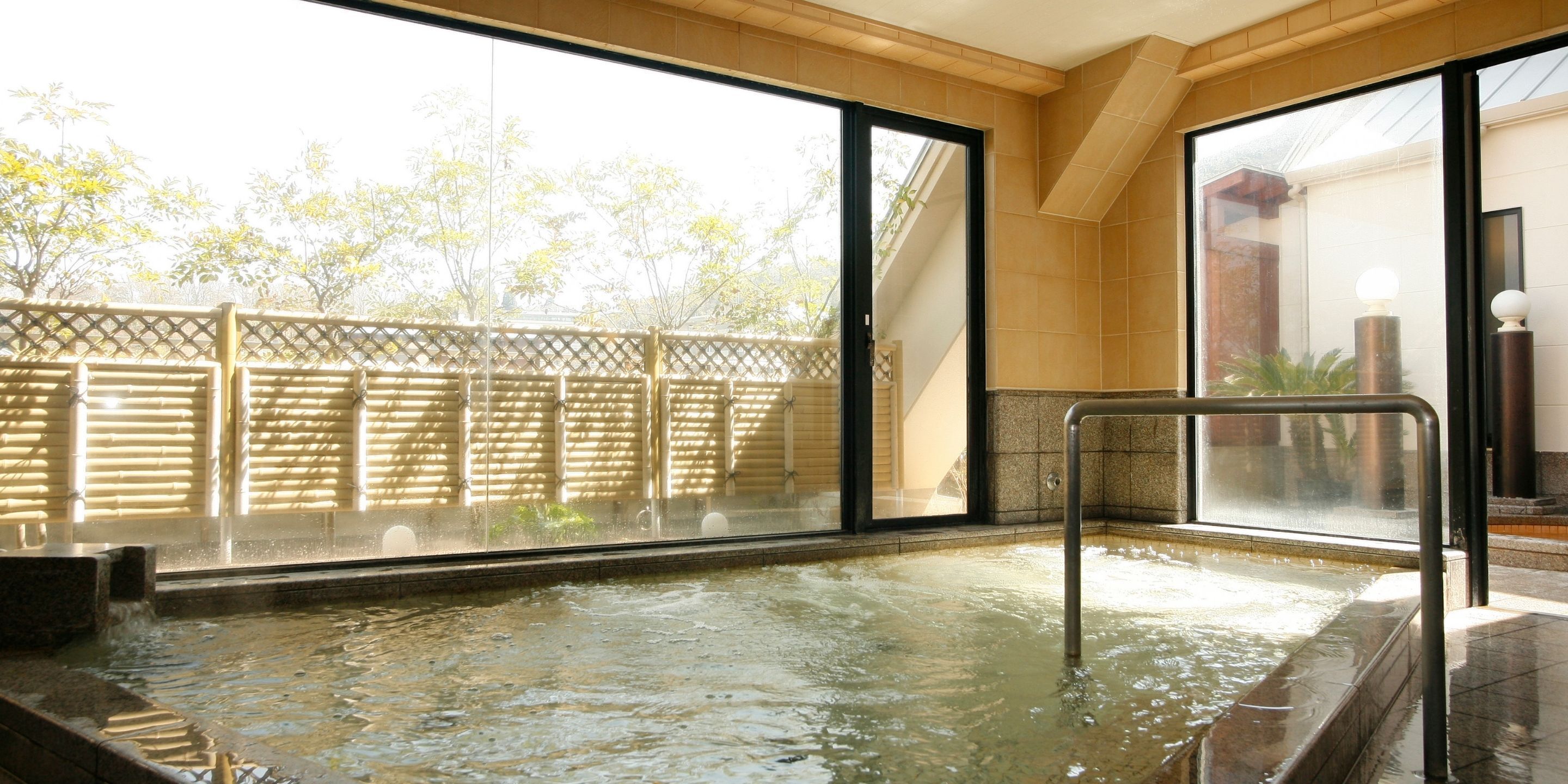 Ein Whirlpoolbereich mit Blick auf Bäume durch große Fenster.