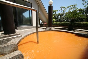 Una piscina con una escalera metálica y un adorno esférico en un pilar.