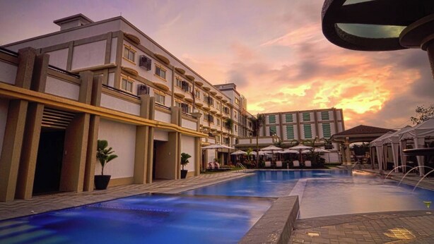 A hotel with a swimming pool, outdoor seating, and a sunset view. - Hotel Centro Puerto Princesa, Palawan (Puerto Princesa)