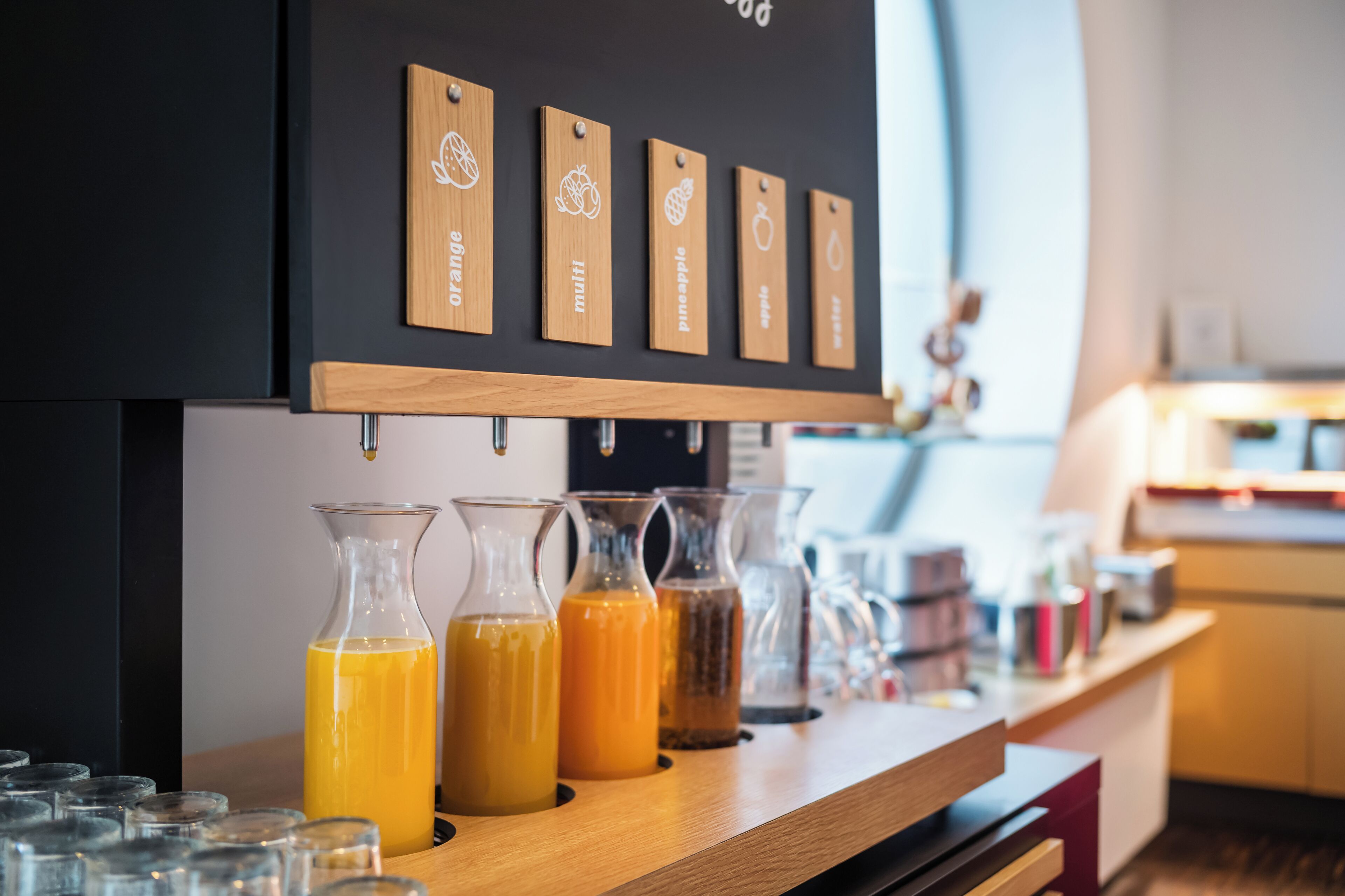 A juice bar with various fruit juices and a wooden sign indicating different juice options.