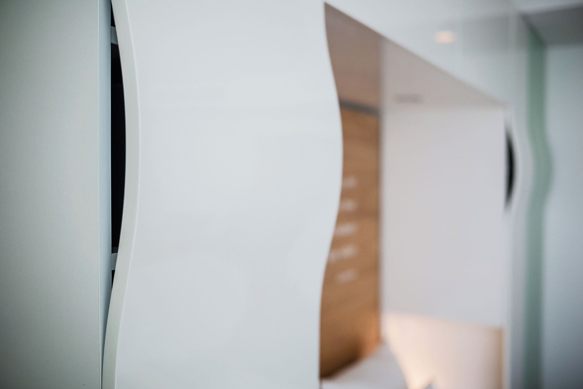 A modern interior with a curved white wall and a wooden panel.