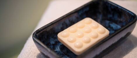 A rectangular black tray with a white soap bar on a white towel.