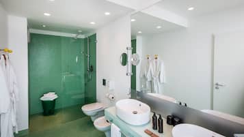 A modern bathroom with a large mirror, two sinks, a shower, and a toilet.