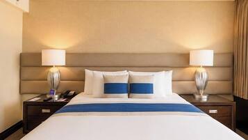 A hotel room with a large bed, two bedside lamps, and a headboard.