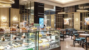 A modern cafe with a glass display case filled with pastries and beverages, comfortable seating, and a clean, well-lit interior.