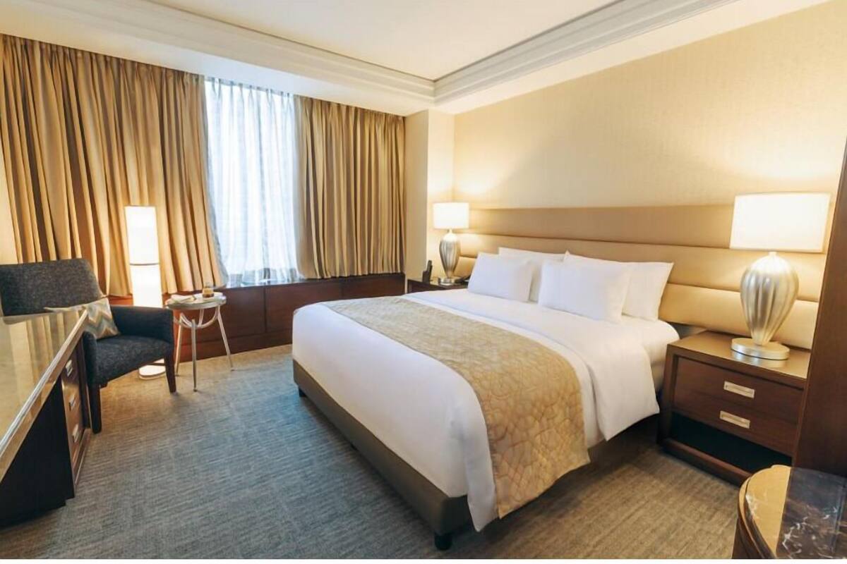 A hotel room with a large bed, bedside tables, a desk, and a chair.