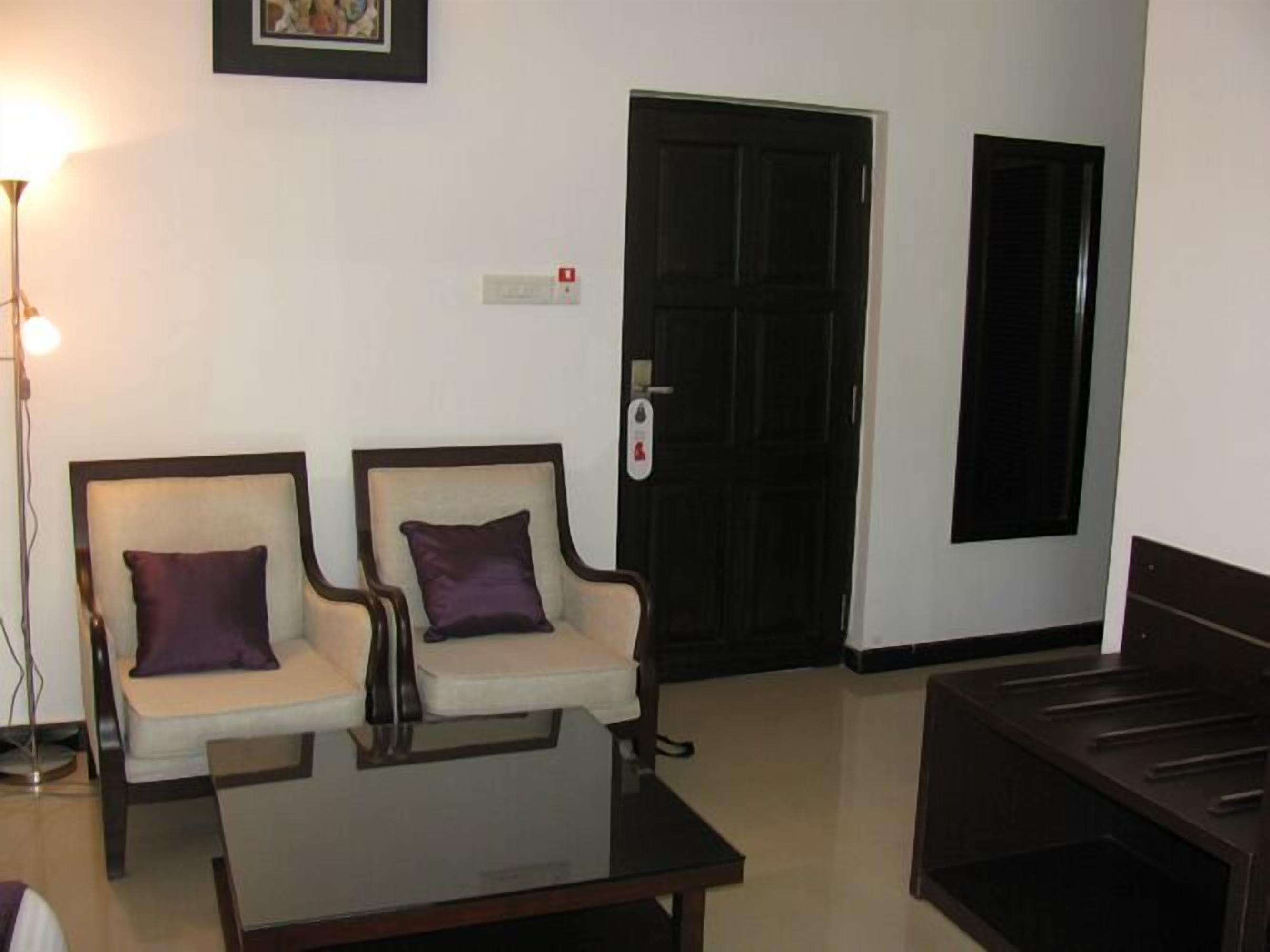 A waiting area with two armchairs, a coffee table, and a door with a security keypad.