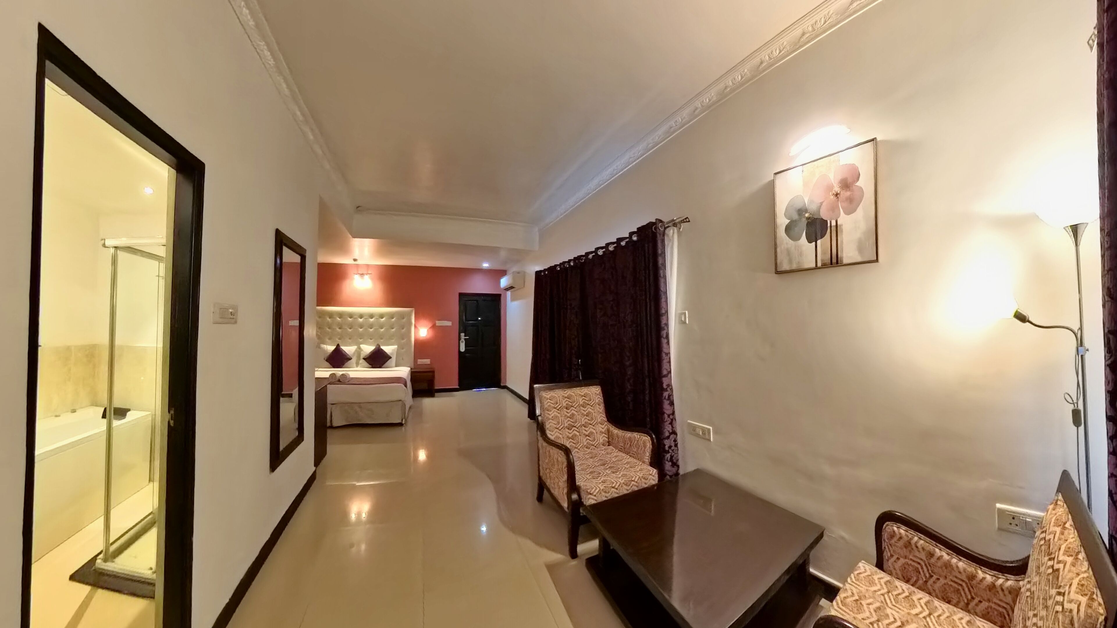 A hotel room with a bed, a chair, a table, and a shower area.