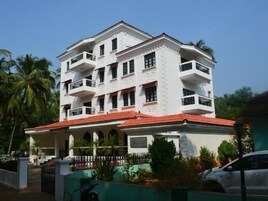Un edificio de varios pisos con balcones, techo rojo y entrada con reja.