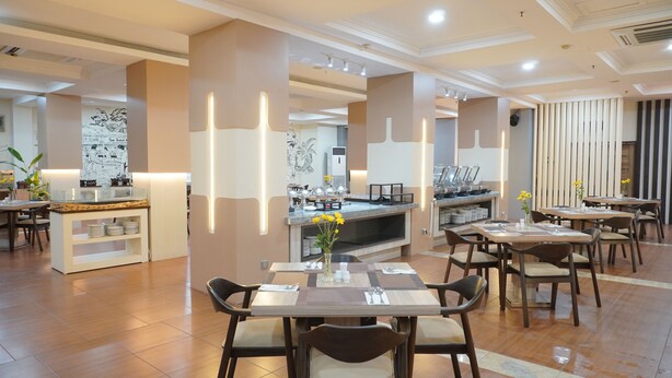 Un espace repas moderne comprenant plusieurs tables et chaises, un buffet et un mur orné d’une fresque.