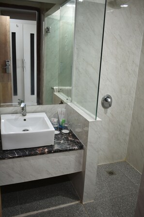 A bathroom with a white sink, a glass shower enclosure, and a marble-tiled floor. - Abadi Hotel Malioboro Jogja (Yogyakarta)