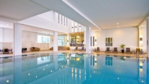 A large indoor swimming pool with clear blue water, surrounded by lounge chairs and a seating area with tables. - Classic Kameo Hotel & Serviced Apartments, Rayong (Rayong)