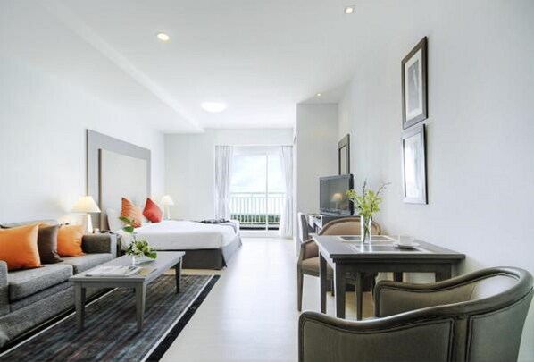 A hotel room with a bed, a sofa, a coffee table, a desk, and a TV.