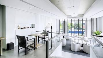 A modern office space with a long table, chairs, and a glass partition.