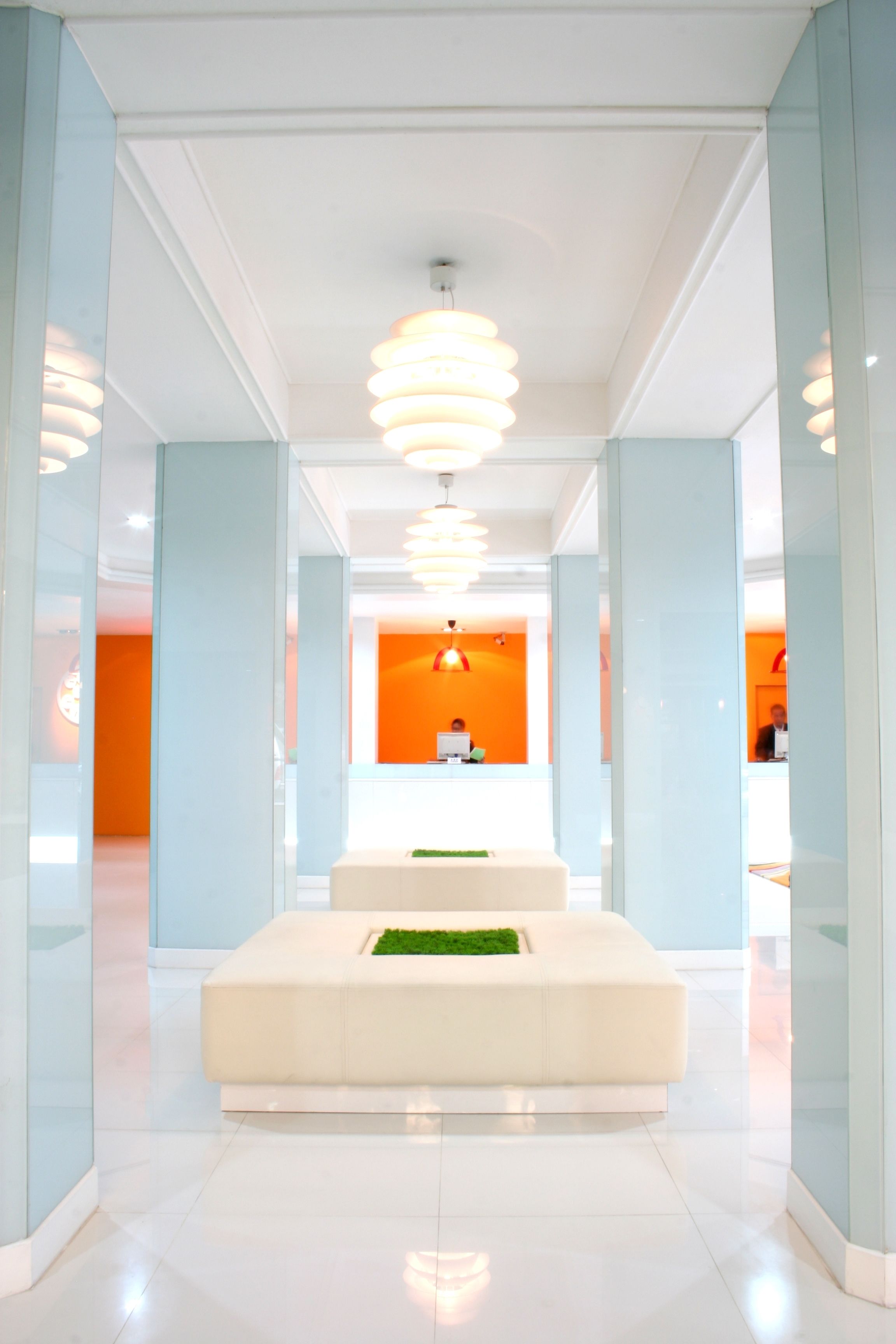 A modern lobby with a reception desk, a white seating area, and a glass partition.